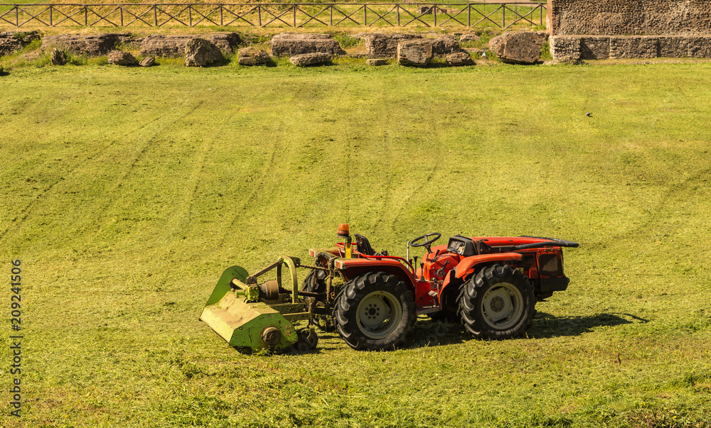 Fototapeta premium Small tractor cutting grass in foro romano ,rome