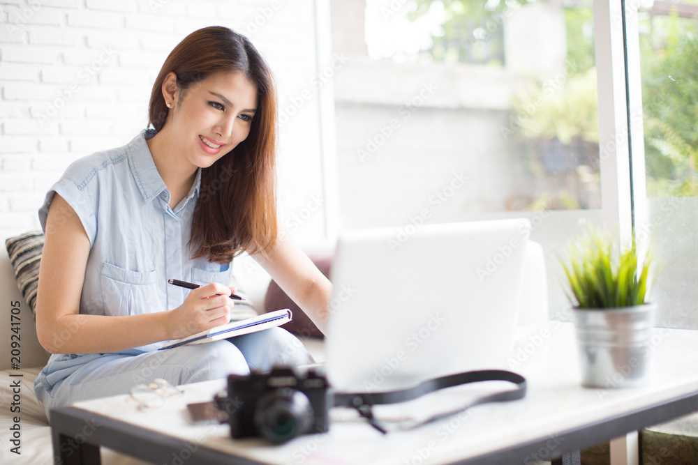 Asia woman using laptop and writing at living room Asia woman using laptop and writing at living room
