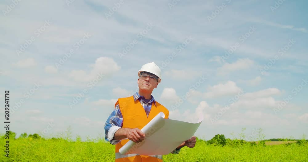 Engineer Analyzing Plan While Looking At Farm Engineer Analyzing Plan While Looking At Farm