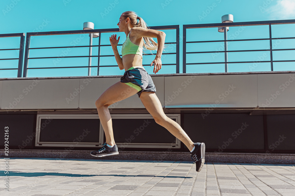 Pretty sporty woman jogging at city