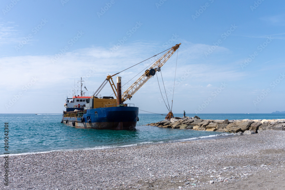 small boat with little crane for maintenance of beach pier in Ligury, Italy small boat with little crane for maintenance of beach pier in Ligury, Italy