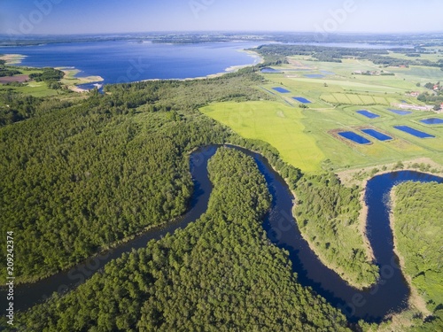 Meander of Wegorapa river flowing across wetlands, Mazury, Poland. Mamry Lake in the background © Mariusz Świtulski