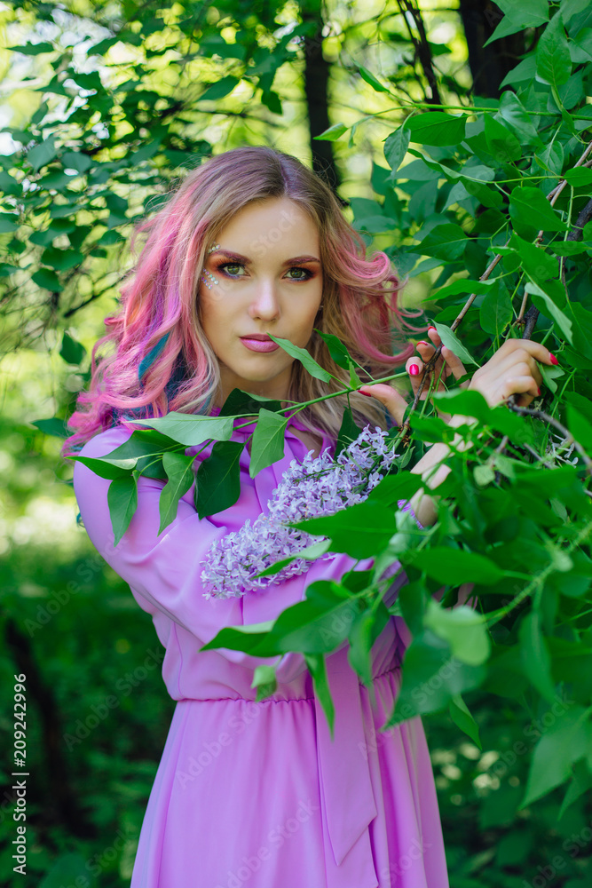Beautiful girl with colorful dyed hair and perfect makeup and hairstyle standig next to lilac bush Beautiful girl with colorful dyed hair and perfect makeup and hairstyle standig next to lilac bush