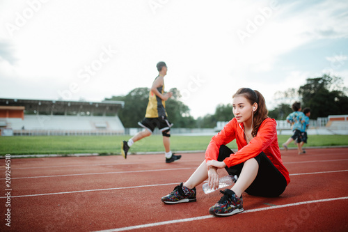 Young woman runner resting after workout session on sunny morning.Asia woman jogger taking a break from running workout. © uinmine