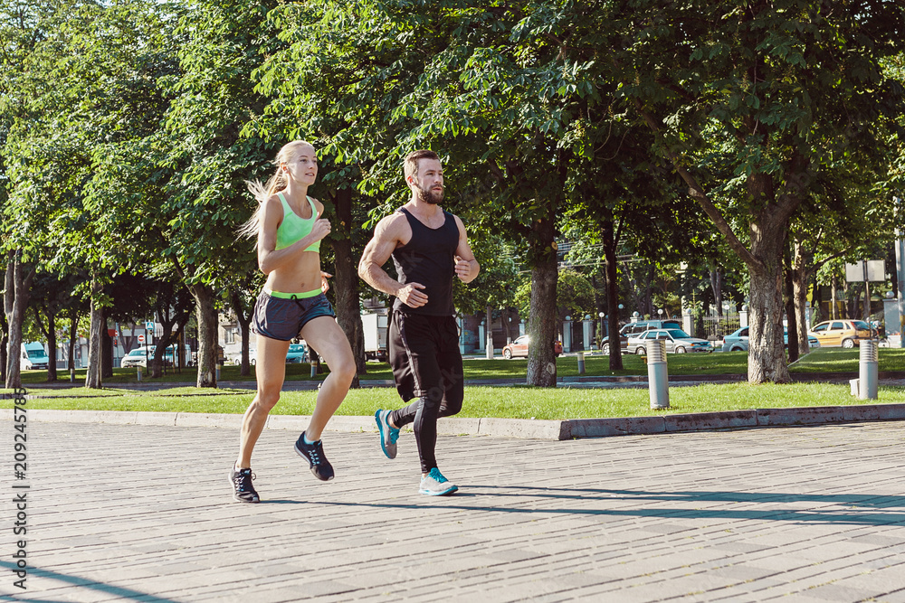 Obraz premium Pretty sporty woman and man jogging at city
