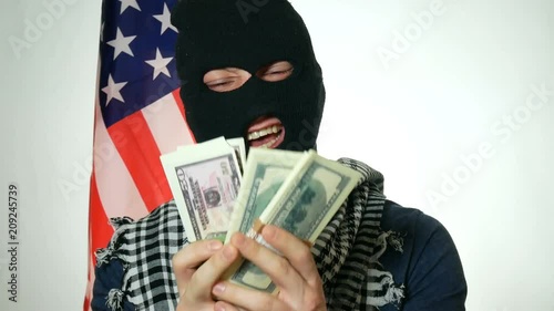 male terrorist shows money and laughs against the background of the flag of America