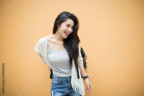 lifestyle fashion portrait of young stylish hipster Asia woman on orange background