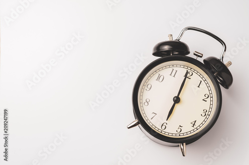 Black vintage alarm clock show 6 o'clock on white background with copy space photo