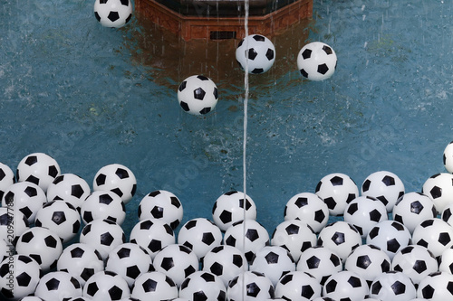 White soccer balls in the blue pool with a water copy space.