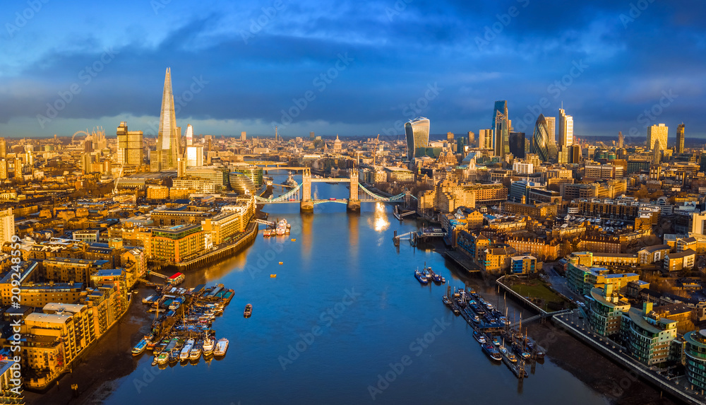 London, England - Panoramic aerial skyline view of London including iconic Tower Bridge with red double-decker bus, skyscrapers of Bank District and other famous skyscrapers at golden hour