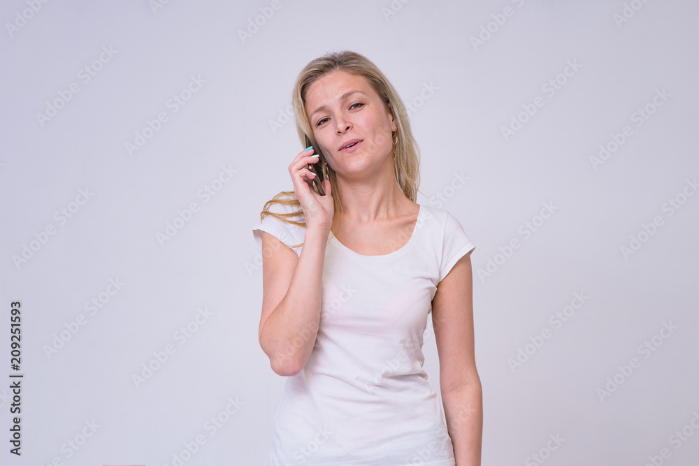 portrait of a beautiful blond girl on a white background interacting with a smartphone portrait of a beautiful blond girl on a white background interacting with a smartphone