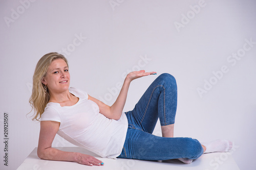 portrait of a beautiful blonde girl on a white background lying on a table. photo