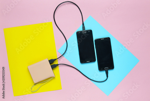 Power bank charged two smartphones on a colored pastel background. Modern gadgets. Top view. Minimalism. photo