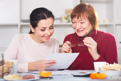 Portrait of mature woman and daughter with documents