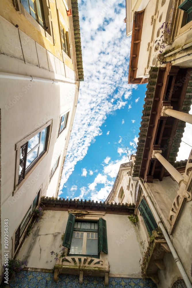 Old buildings viewed from bottom looking up with blue sky during the day in Italy