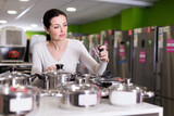 Female choosing cooking pot  in  household appliances section