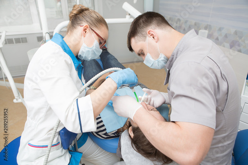 dentists examining and working on patient. Healthy Smile.  Doctor doing dental treatment on man s teeth in the dentists chair.