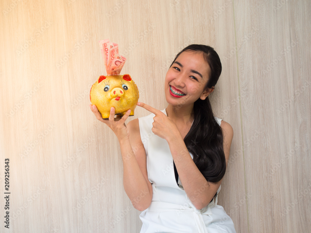 Smiley asian woman holds golden Piggy bank. Banking and finance concept. Smiley asian woman holds golden Piggy bank. Banking and finance concept.