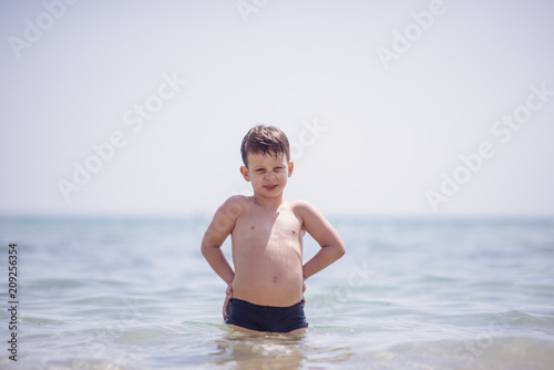 Adorable boy standing in the water on the beach