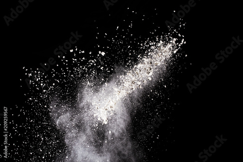  Freeze motion of white dust explosion on black background. Stopping the movement of white powder on dark background. Explosive powder white on black background.
