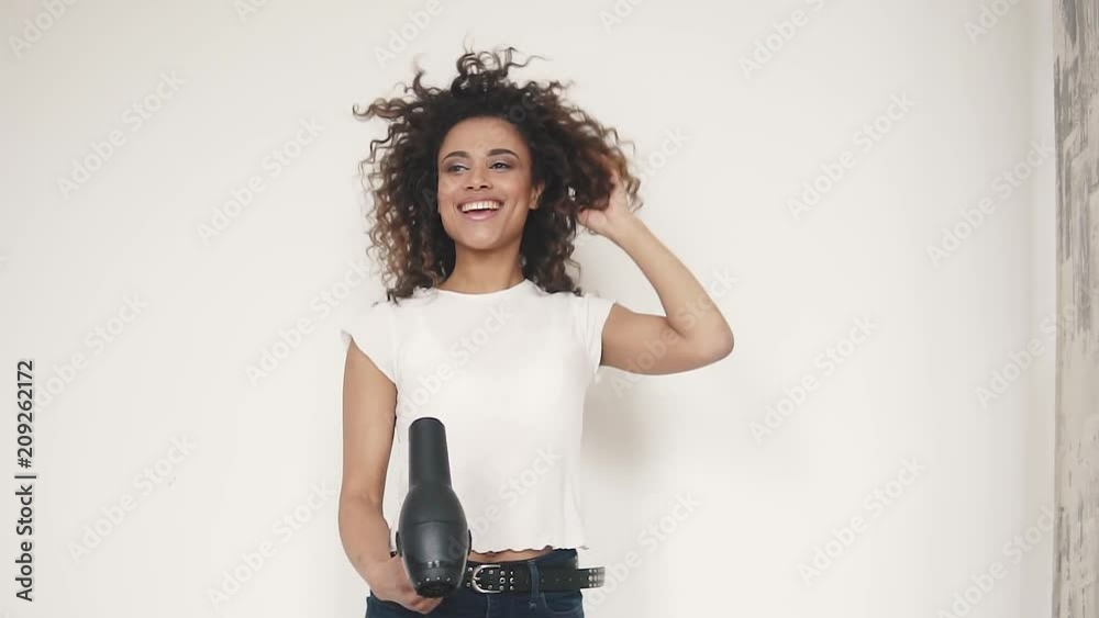 young curly-haired girl sings in a hair dryer and dances at home young curly-haired girl sings in a hair dryer and dances at home