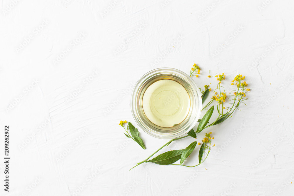 Sprigs of winter cress with a bowl of vegetable oil on a white background. - obrazy, fototapety, plakaty 