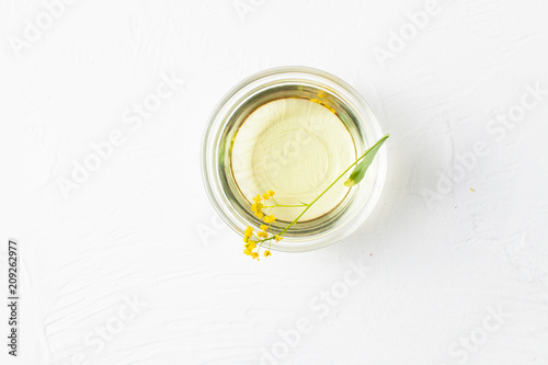 Sprigs of winter cress with a bowl of vegetable oil on a white background.