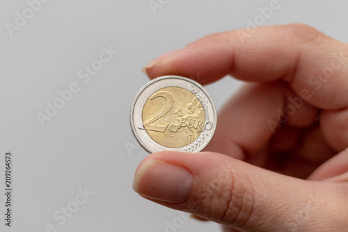 Two Euro coin between the fingers of a woman 