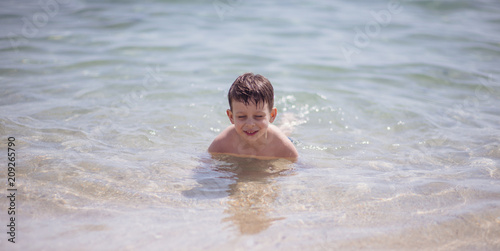 Adorable young kid sitting in the water on the beach © qunica.com