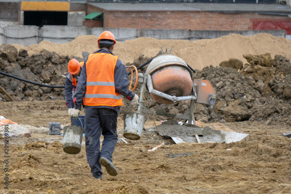 workers at the construction site prepare concrete mixer