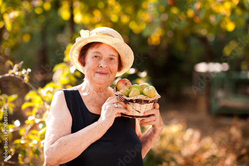 Happy senior woman with fruits outdoors. Looking at camera. Healthy lifestyle. 70s.