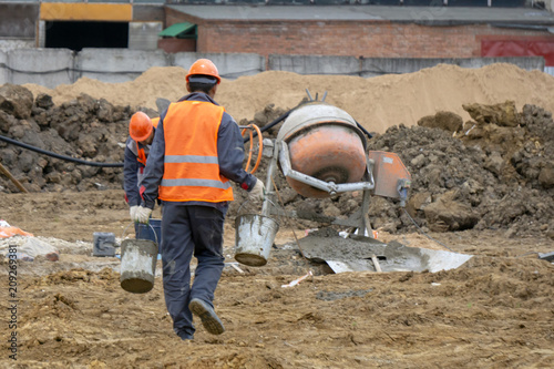 workers at the construction site prepare concrete mixer