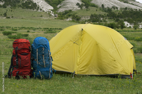 Two tourist backpacks near the assault tent in a mountainous area