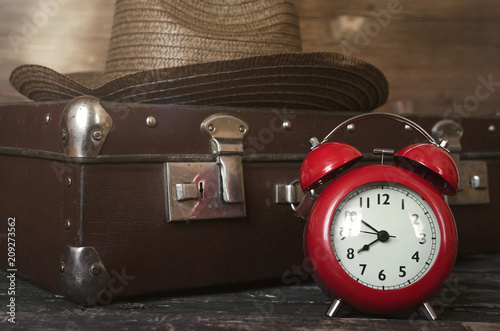 Retro summer sea vacation background. Vintage suitcase, tourist hat and red alarm clock. Time to relax concept.