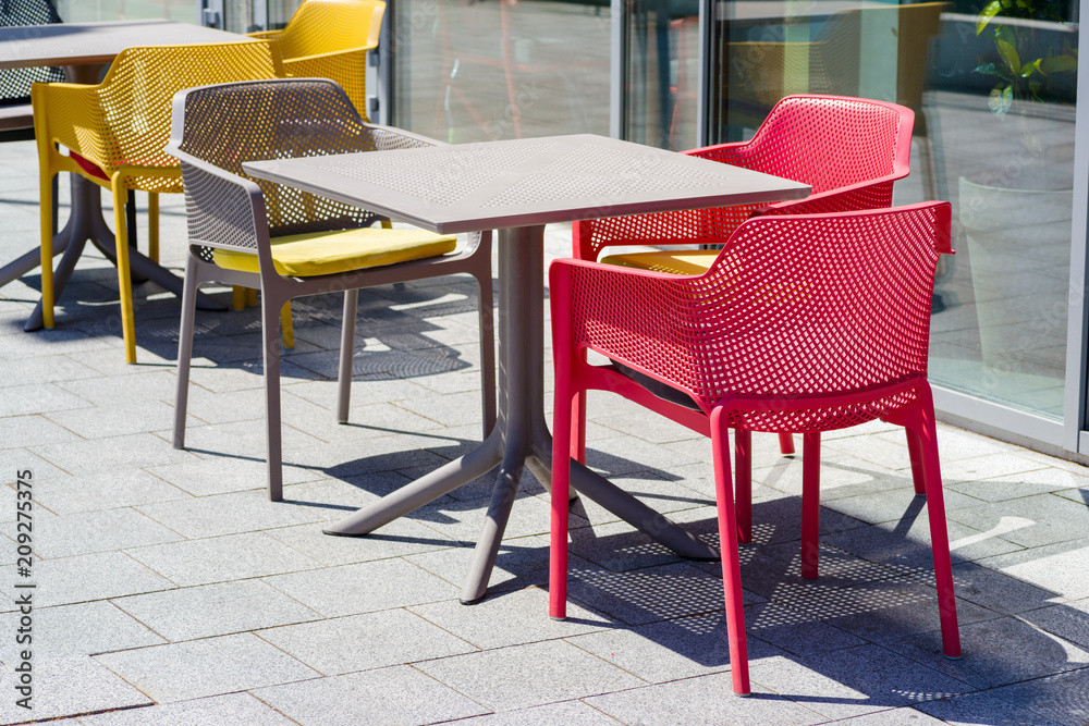 tables and chairs on the street on a sunny day near a cafe
