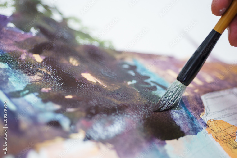 Artist makes the first brush strokes on a clean canvas while painting a watercolor painting. Artist makes the first brush strokes on a clean canvas while painting a watercolor painting.