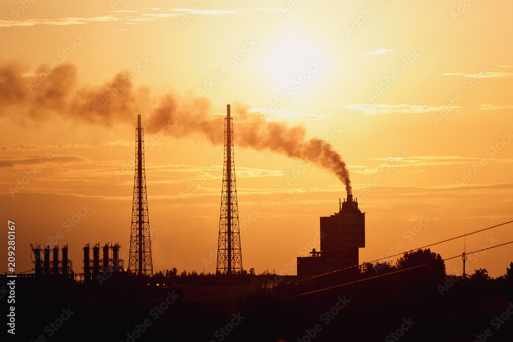 Silhouette power plant with cooling towers against sunset sky