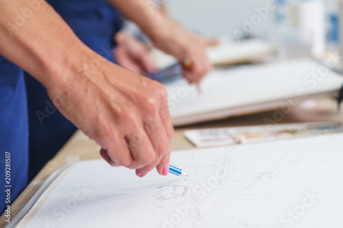 Artist sketches a pencil in a school of painting, preparing a blank canvas for the creation of a painting.