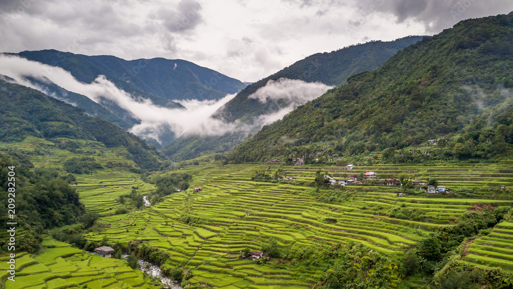Aerial drone view of huge rice terraces in a valley surrounded by tall mountains and low hanging cloud (Banaue) Aerial drone view of huge rice terraces in a valley surrounded by tall mountains and low hanging cloud (Banaue)
