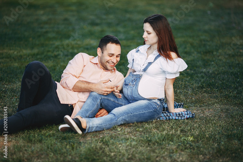 Family conversation. Father talking to his unborn child. Pregnant couple sitting in the park chatting. Relations, maternity, family, parenthood, love concept © Vadym