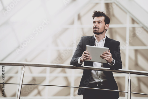 Thoughtful businessman with tablet in hands.