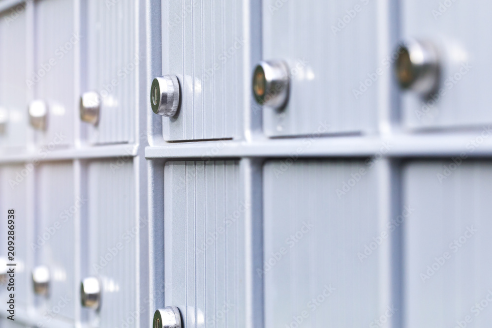 Metal mailboxes and lock in business center of an urban neighborhood. Mail boxes in rows at entrance of modern building. Security storage mailroom for secret files or corporate postal service. Metal mailboxes and lock in business center of an urban neighborhood. Mail boxes in rows at entrance of modern building. Security storage mailroom for secret files or corporate postal service.