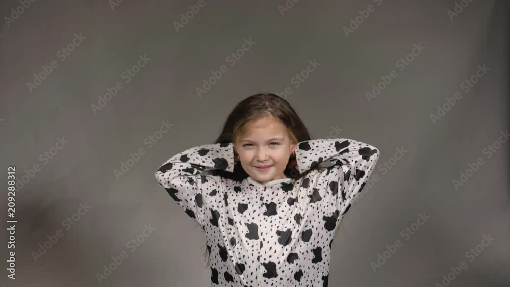 Happy little girl in the studio on a gray background. She jumps, shows different emotions. Hair fluttering from the wind. Super slow motion, shot at 180fps. Happy little girl in the studio on a gray background. She jumps, shows different emotions. Hair fluttering from the wind. Super slow motion, shot at 180fps.