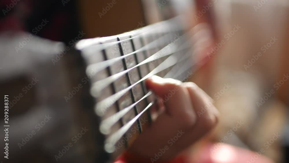 Teen girl playing guitar at home. Close up of cute teen indoors in a hoody softly strumming her guitar.