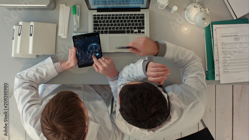 Top view of Doctors discussing images of x-ray scan on tablet