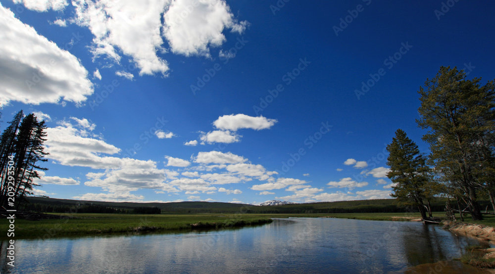 Gibbon River under cloudy blue skies in Gibbon Meadows in Yellowstone National Park in Wyoming United States