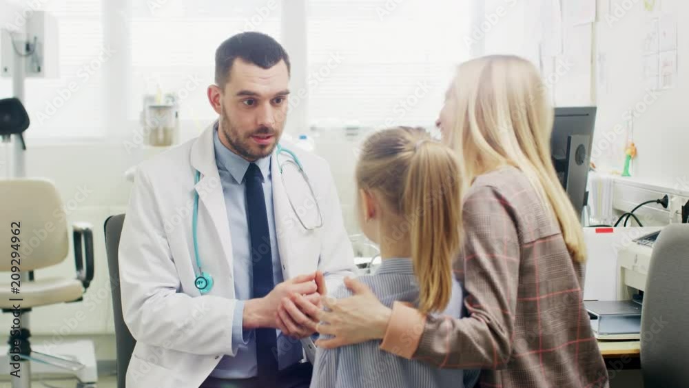 Friendly Doctor Does Routine Examination of a Sweet Little Girl who Came with Her Mother. Pediatrician Talks to Both of them. Doctor's Office is Bright and Modern. Friendly Doctor Does Routine Examination of a Sweet Little Girl who Came with Her Mother. Pediatrician Talks to Both of them. Doctor's Office is Bright and Modern.
