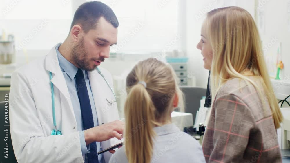 Doctor Diagnoses Little Girl, He Uses Digital Tablet Computer to Browse Through Medical History of the Healthy and Happy Child Doctor Diagnoses Little Girl, He Uses Digital Tablet Computer to Browse Through Medical History of the Healthy and Happy Child