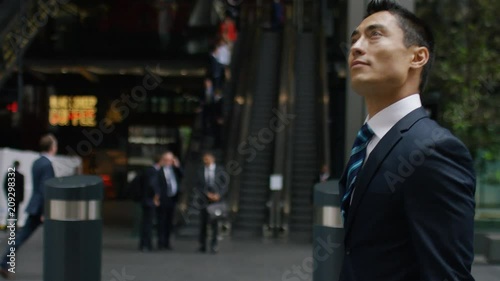 Handsome asian business man walks through the city, in slow motion