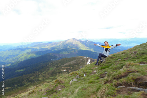 Young free female tourist wearing yellow jacket sitting in Appenine mountains. Concept of spending summer vacations in Alps, tourism and traveling. photo